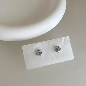 Macro detail of silver moon earrings featuring blue cat-eye stone and sparkling zircons