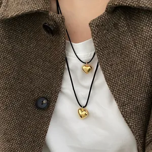 Detail of layered gold heart pendants on a black woven cord necklace for women