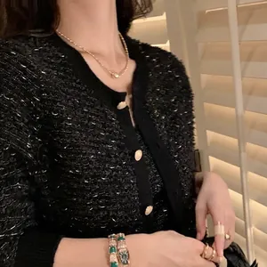 Nahaufnahme der schwarzen Tweed-Strickjacke mit goldenen Knöpfen und schickem Schmuck