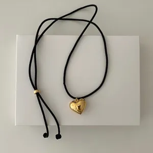Detailed view of polished gold 3D heart pendant with adjustable black braided cord necklace