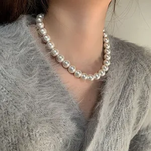 Gros plan d'un collier de perles crème de 12 mm porté sur le cou au style élégant