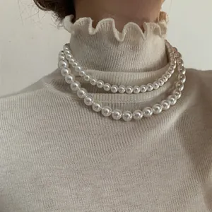 Gros plan d'un collier double rang en perles de verre sur un haut à col montant
