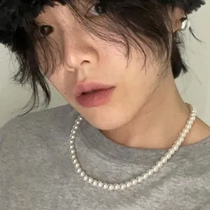 Détail d'un collier de perles de verre blanches élégant porté par un mannequin en tenue décontractée