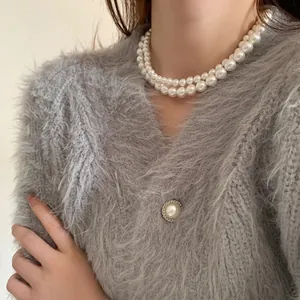 Gros plan sur un collier double rang en perles de verre porté sur un pull gris