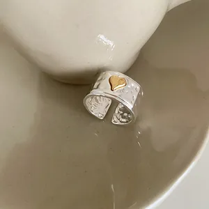 Detailed macro view of silver hammered metal wide ring with small gold heart accent