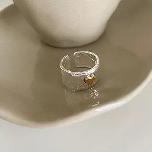 Detail of vintage textured silver ring with a gold heart on a ceramic plate