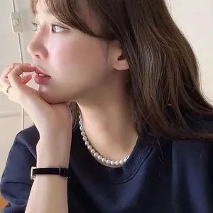 Vue détaillée d'un collier de perles de verre élégant porté sur un sweat-shirt bleu marine