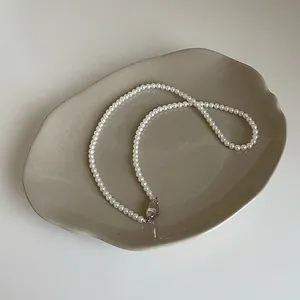 Détail du collier de perles de verre blanc avec fermoir argenté sur plateau