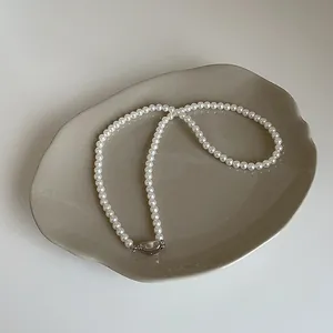 Détail d'un collier de perles blanches avec un fermoir rectangulaire argenté poli