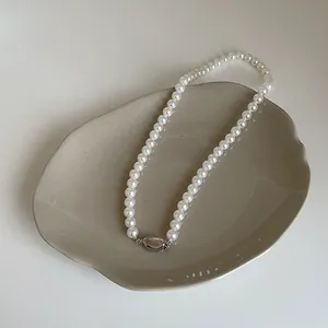 Détail du collier de perles de verre avec fermoir haricot argenté sur plateau céramique
