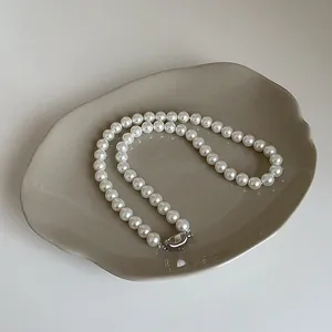 Détail de perles de verre blanches élégantes avec fermoir en métal sur plateau