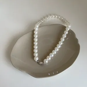 Détail d'un collier de perles en verre élégant avec fermoir argenté sur plateau