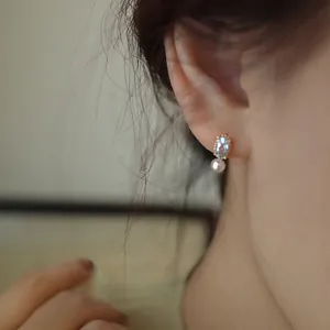 Orecchini dorati con pietre preziose blu e perle indossati da una modella elegante