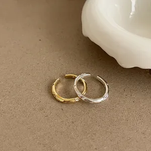 Irregular textured gold and silver zircon open rings set on a soft warm grey background