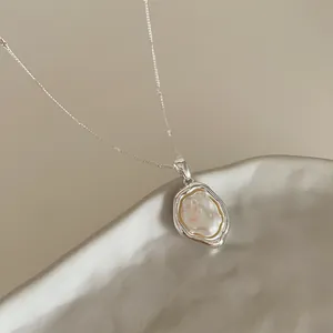 Dettaglio macro del ciondolo d'argento irregolare con perla barocca su catena sottile