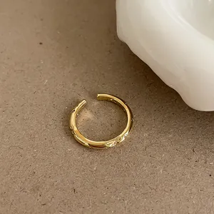 Detailed close-up of a gold adjustable ring with polished finish and circular groove patterns
