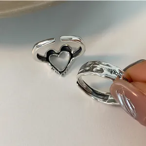Close-up of S925 silver rings featuring a hollow heart and hammered texture with engraving