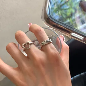 Irregular heart ring set with engraved lettering shown on hand holding glass