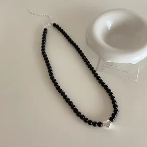 Close-up of black beaded necklace with a silver heart pendant and adjustable clasp