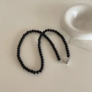 Close-up of black beaded necklace with a polished silver heart-shaped toggle clasp
