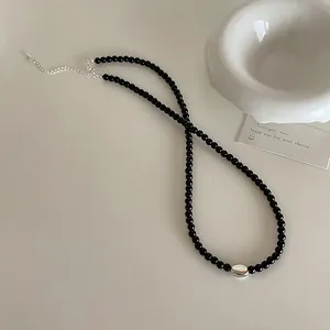 Detail of black beaded necklace with silver oval bead and adjustable lobster clasp