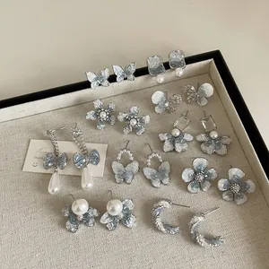 Set of 9 blue gradient crystal stud earrings with bow and flower designs on a tray
