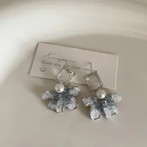 Elegant blue gradient floral stud earrings with pearls and crystal accents on a white tray