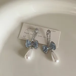 Detailed macro view of blue gradient crystal bow earrings with white pearl drops