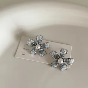 Detailed view of flower earrings with blue gradient crystal petals and center pearl