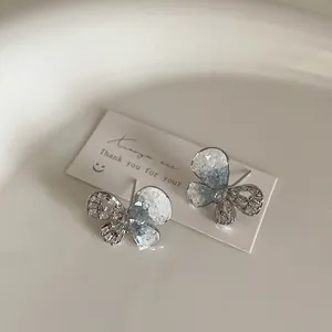 Detailed shot of blue crystal butterfly earrings with silver hollow wing design