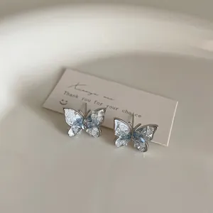 Close-up of blue gradient crystal butterfly earrings on a minimalist display card