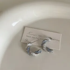 Macro detail of blue crystal bow flower stud earrings on cream jewelry card