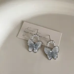 Detailed macro view of silver bow earrings with blue gradient crystals and white pearls