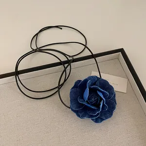 Detail of blue denim rose necklace showing layered petals with frayed edges and long cords
