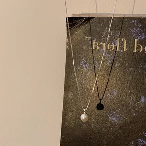 Gros plan d'un pendentif en perle d'eau douce sur une fine chaîne argentée élégante