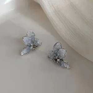 Close-up of butterfly stud earrings with blue ice-crack crystal and silver edges