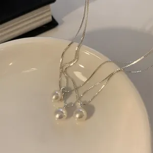 Trois colliers de perles d'eau douce avec chaînes argentées sur un plateau en céramique