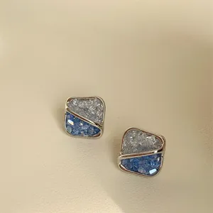 Macro view of square earrings with blue and clear crystals in silver-tone setting