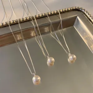 Détail de trois colliers de perles d'eau douce avec chaînes en argent sur un plateau