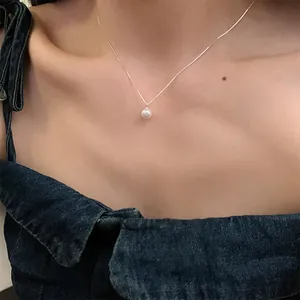Détail d'un collier de perles d'eau douce minimaliste sur un modèle avec chaîne argentée