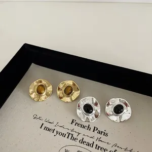 Vintage irregular hammered metal earrings with oval natural stone on display tray