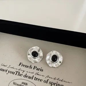 Detailed close-up of silver irregular hammered earrings with black oval natural stone