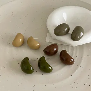 Boucles d'oreilles minimalistes en résine en forme de haricot sur un plat en céramique