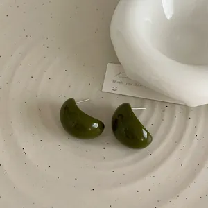 Gros plan sur les boucles d'oreilles semi-circulaires en résine vert foncé sur céramique