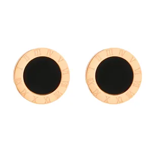Macro view of rose gold stud earrings featuring Roman numerals and black circular inlays