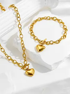 Detailed view of chunky gold chain link necklace and bracelet set with heart pendants