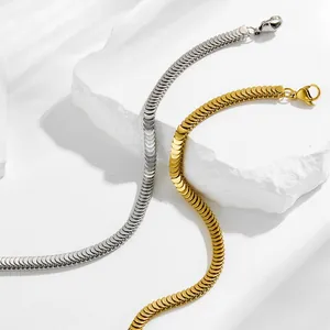 Gold- und Silber-Schlangenknochen-Armbänder auf strukturiertem Stein mit Blatt Schatten