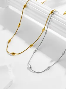 Detailed view of layered gold and silver snake chains with polished metal beads on pillars
