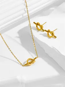 Detailed view of matte 18K gold knot pendant necklace and stud earrings set on stone