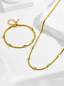 Dettaglio del set collana e bracciale a catena serpente dorata con zirconi verde smeraldo